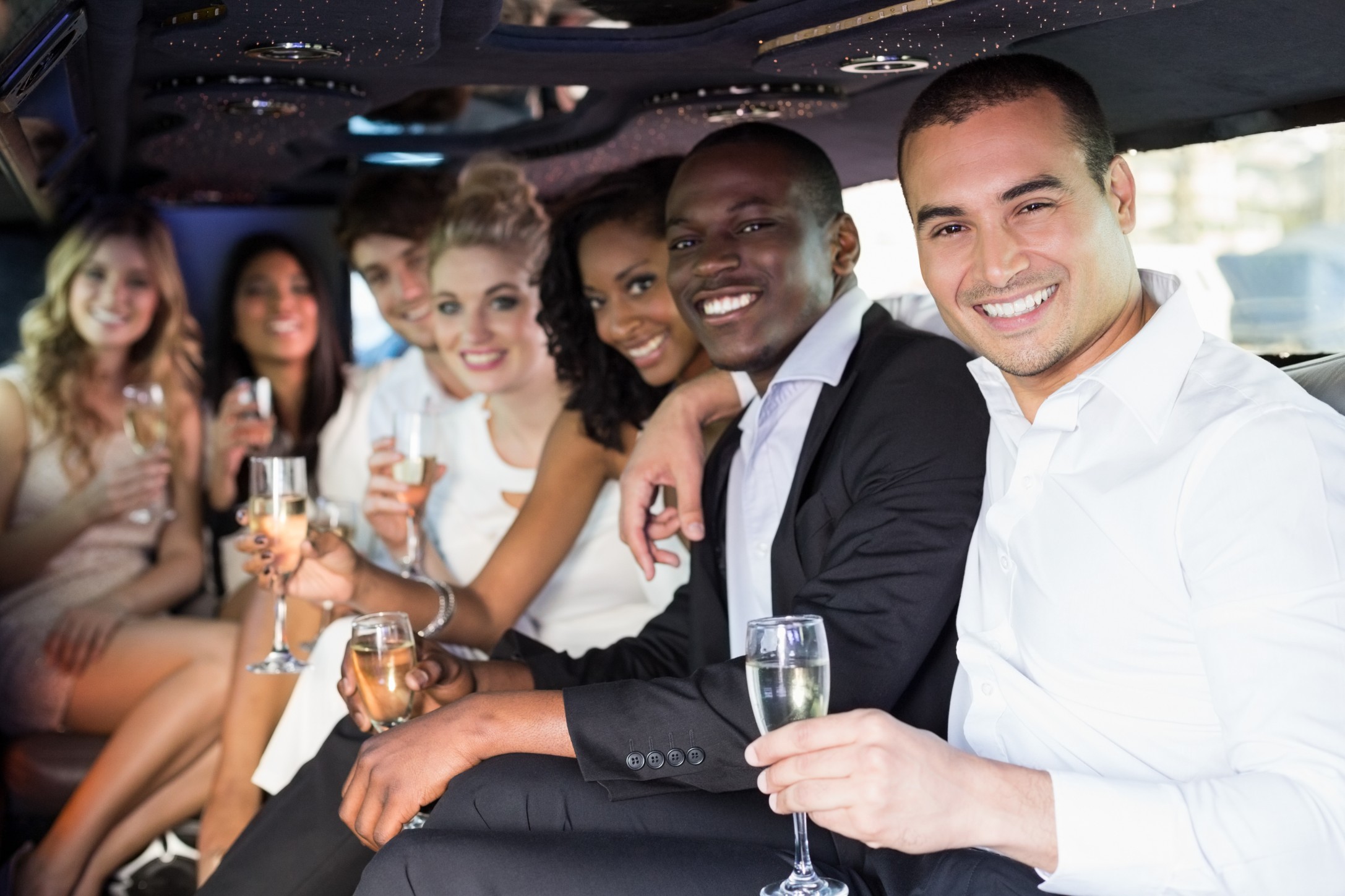 adults driving to a rehearsal dinner in a limousine